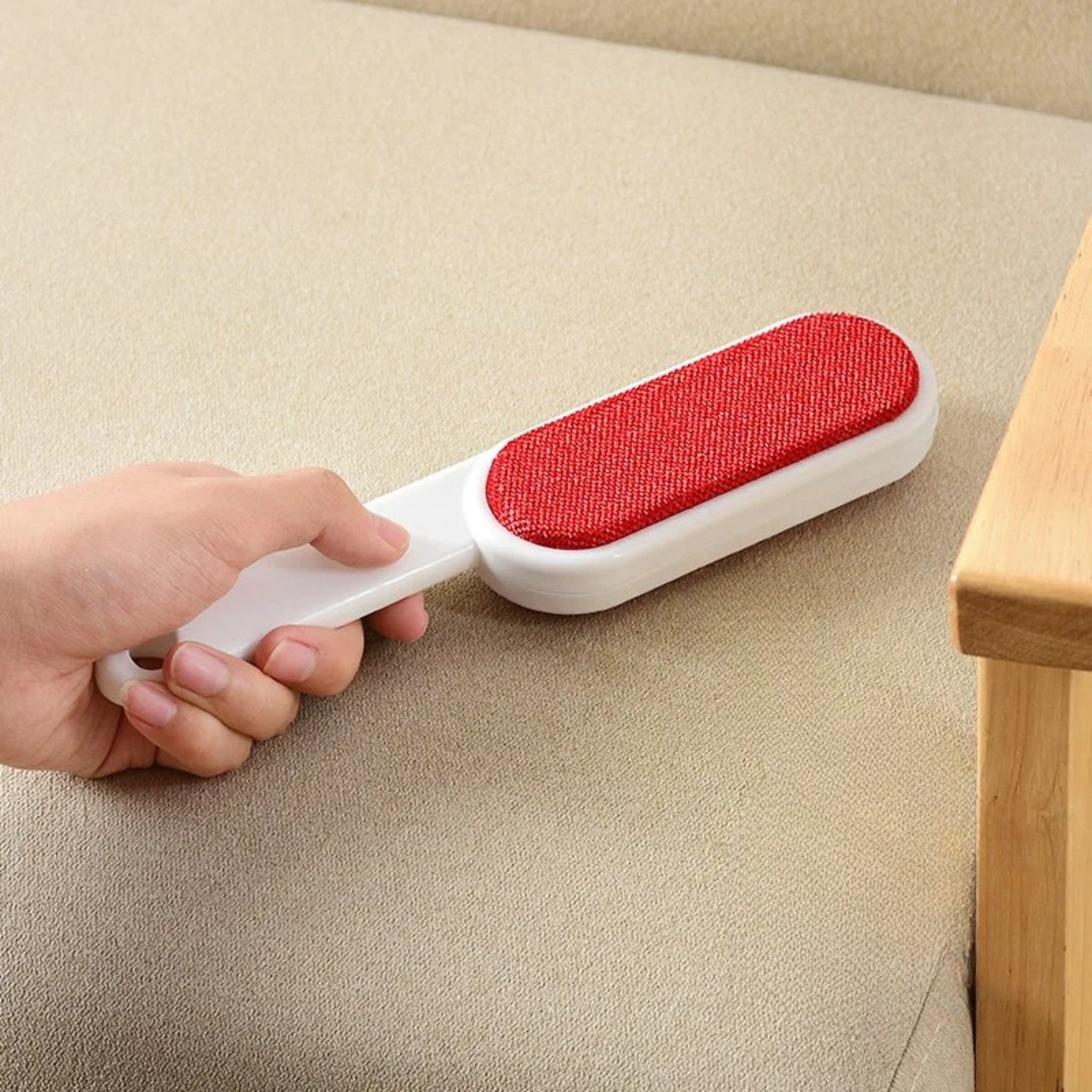 Brosse électrostatique anti-poils sur canapé cuir avec poils de chien rouge
